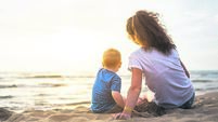 Mother with little baby boy at the beach on sunset