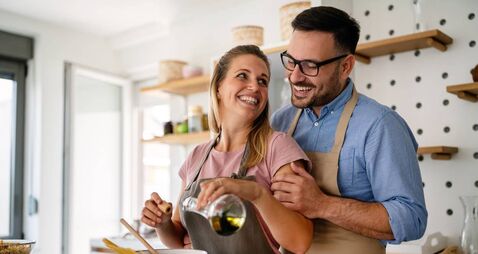 Young happy couple is enjoying and preparing healthy meal in their kitchen together