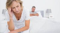 Upset couple sitting on opposite ends of bed after a fight