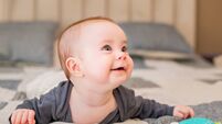 half-year-old baby lies on the bed smiling