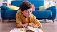Young Child Engrossed in Reading a Colorful Book on Floor