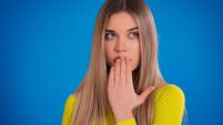 shocked beautiful woman covering mouth on blue background