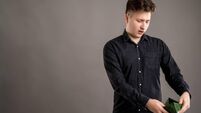 Portrait of serious stylish attractive man dressed with a casual black shirt looking at the empty wallet