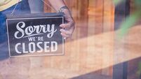 Woman Holding up a shop sign saying: Sorry we're Closed