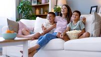 Mother with sons on sofa enjoying home movie night.