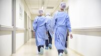 Team of medical staff in personal protective equipment walking in hospital corridor