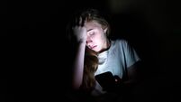 Upset girl on her smartphone in the dark.