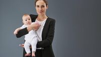 Good-looking mom with baby on hands looking at camera