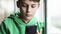 Boy with smartphone indoors. Preteen boy using a phone checking social media. Concept of children using the smartphone