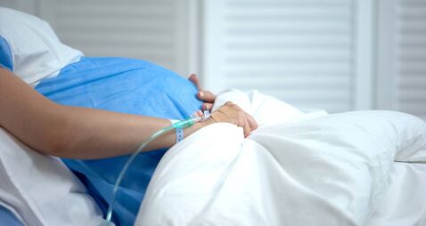 Pregnant woman holding blanket, feeling abdominal pain, risk of miscarriage