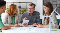 Business colleagues discussing over digital tablet while sitting at desk in office during meeting