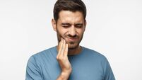 Tooth ache concept. Indoor shot of young male feeling pain, holding his cheek with hand, suffering from bad toothache, looking a