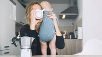 Modern tired mother and little child after sleepless night. Exhausted woman with baby is sitting with coffee in kitchen. Life of