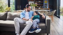 Dad talking with his smiling little son on a sofa at home