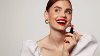 Beautiful emotional woman with bright make-up applying red lipstick