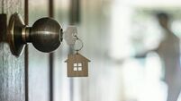 House key with home keyring in keyhole on wood door, copy space