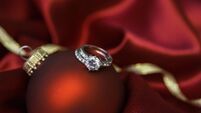 Christmas bauble with wedding and engagement rings in red satin