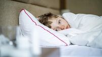 School age boy laying in bed with a flu