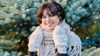 Portrait of young woman in knitted scarf mittens in winter, near Christmas tree