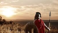 Warrior wearing iron helmet and red cloak.