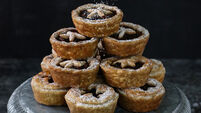 Image of icing sugar being sifted onto batch homemade, mince pies, star shaped pastry lids, festive Christmas dessert of crispy