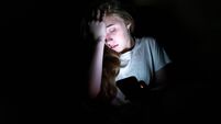 Upset girl on her smartphone in the dark.