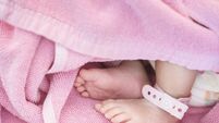 Closeup foot of baby with newborn ankle tag on bed in hospital textured background