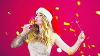 woman in santa hat with champagne and sparklers in red room with gold canfeti.